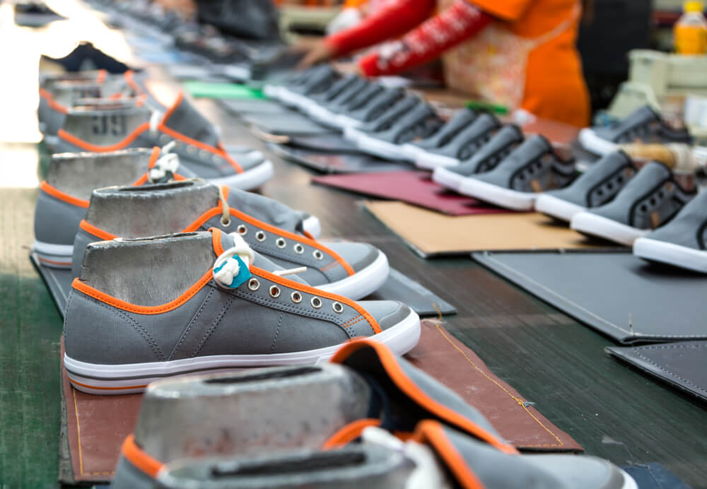 Shoes being assembled and having laces added.